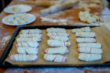 black baking sheet with sausage in the dough