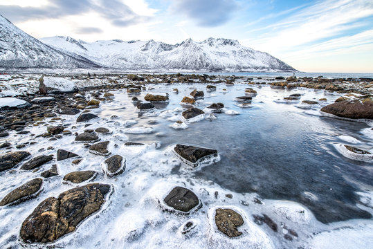 Norwegen, Troms, Torsken, K&uuml;ste bei Ballesvika, der schwankende Wasserspiegel bildet an den Steinen einen Eiskragen