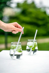 Beautiful glass of water or mojito with lime and mint cocktail on the gree background and white table summer vibe and atmosphere