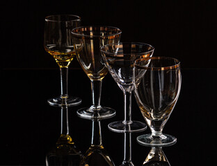Group of four different glasses with nice reflection on black backdrop
