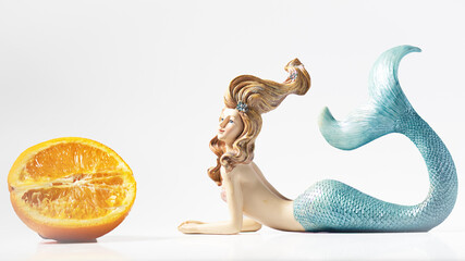 Healthy mermaid looks at orange half