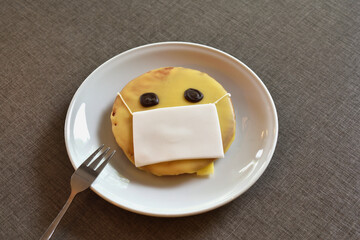 Iced cookies on a white plate. Image of a face in a corona virus mask.