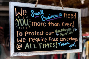 Sign on business re-opening after covid 19 requiring facemask