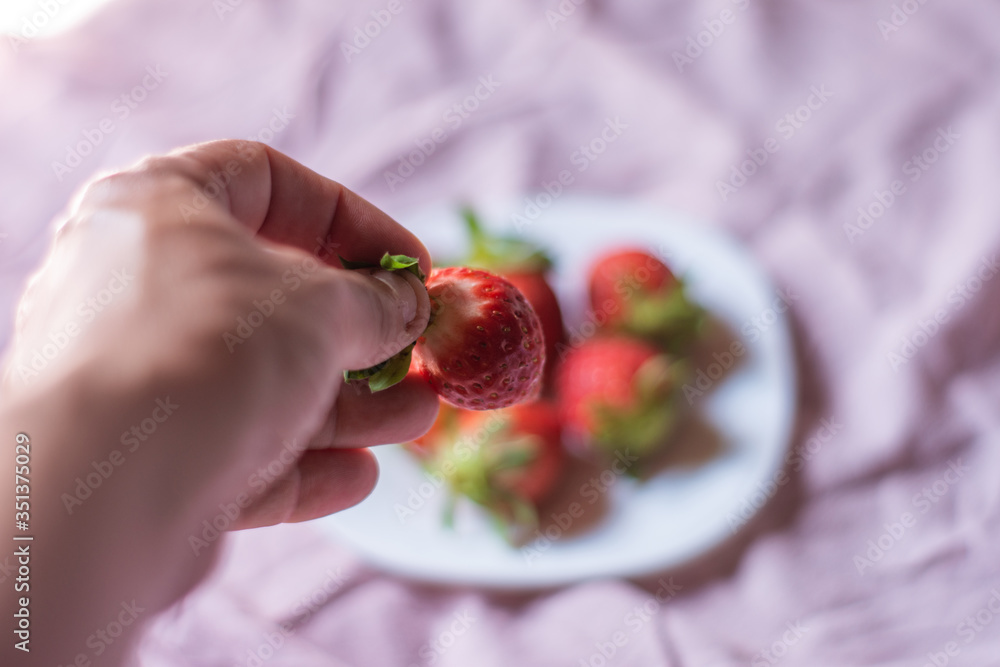 Wall mural portrait of a man's hand with a strawberry. concept: breakfast, diet, healthy