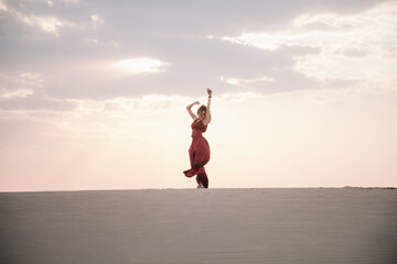 Girl in red dress at sunset in the desert