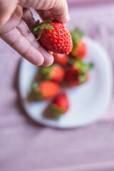 Portrait of a man's hand with a strawberry. Concept: breakfast, diet, healthy