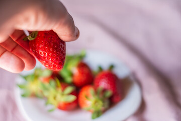 Portrait of a man's hand with a strawberry. Concept: breakfast,