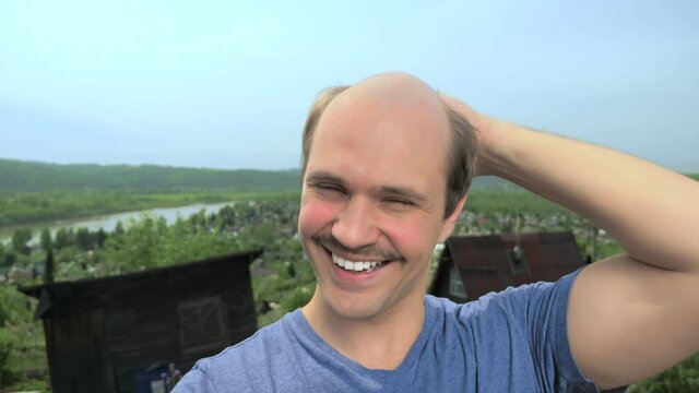 portrait, balding young man in the countryside looking at the camera, smiling
