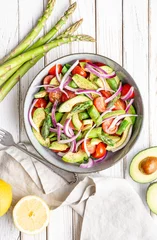 Fototapeten Healthy vegan meal, Juicy summer salad with blanched asparagus, cherry tomatoes, avocado slices and red onion, sprinkled with pepper and drizzled with olive oil and lemon juice © Marcus Z-pics