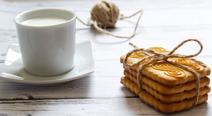 Cookies stacked and a cup of milk on a wooden background. Healthy snack.