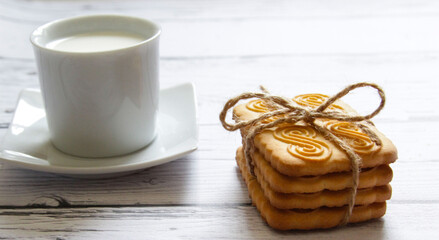 Cookies stacked and a cup of milk on a wooden background. Healthy snack.