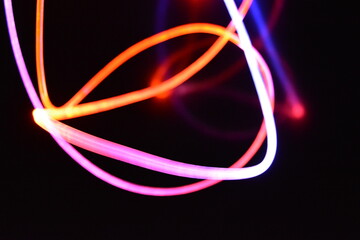 Orange and blue light wire, a light guide wire with different light transmission, light spectrum, and light effects located in a chaotic state with light reflection on a black glossy background.