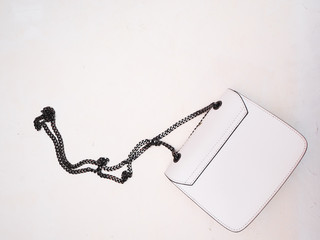 White bag with a black chain on a white textured background. Copyspace.