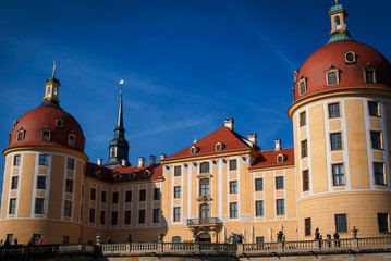 Entrance to Moritzburg Castle, Germany. Beautiful yellow castle with a red roof against a blue sky on a sunny day.