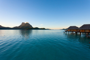 Bora Bora lagoon with overwater huts at sunrise