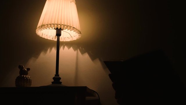 Woman turning off the light after reading book in evening at home