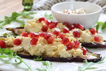 Baked eggplant with cheese, nuts and pomegranate served with garlic sauce