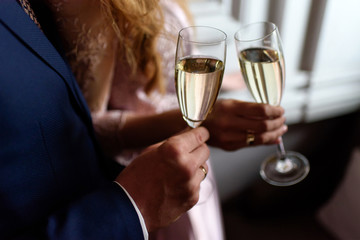 Man and a woman hands holding two glasses of champagne or wine. Couple in a romantic engagement or anniversary celebration. Close-up, selective focus.