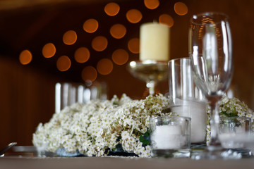Spring wedding decor in rustic styles. Wedding table with glasses, candles and white flowers close-up selective focus