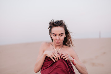 Fototapeta na wymiar Girl with red cloth in the sunset rays in the desert