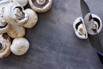 Top view of edible mushrooms - group of white champignons and knife. Cooking harvest fresh food.