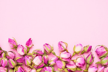 Border of Dried pink roses for tea on pink background. Top view, copy space