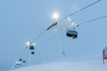 People on ski lift in winter resort - Holidays, snow gear renting, skiing, snowboarding and mountain landscape concept - Focus on guys sitting in cable car