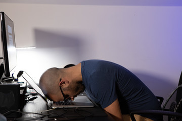 Stressed caucasian man with his head on the computer. Young boy with head on his laptop. Stress concept
