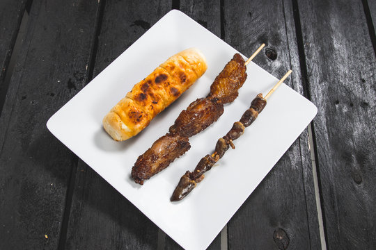 Espetinhos assados de frango asa ou tulipa, cora&ccedil;&atilde;o de frango com p&atilde;o de alho assado servido em prato no boteco