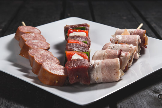 Espetinhos crus de carne com legumes, lingui&ccedil;a calabresa e medalh&atilde;o de frango ou carne servido em prato no boteco