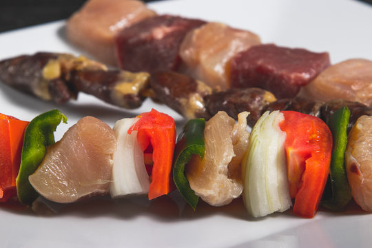 Espetinhos crus de carne, cora&ccedil;&atilde;o de frango e frango com legumes no boteco