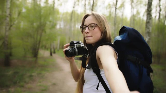 Young woman holding her boyfriends hand while taking photos in the forest. Travel concept