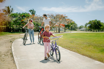 bike ride. family walks in the park on a sunny day. there are seven face masks of different colors on the faces, against the coronavirus covid-19