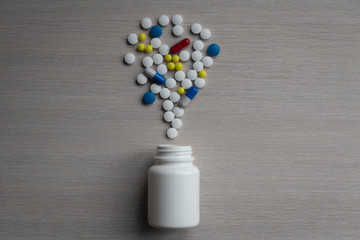 Assorted pharmaceutical medicine pills, tablets and capsules and bottle on gray background
