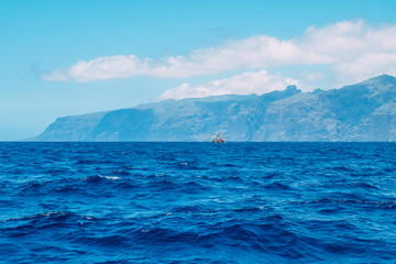 Ship against the background of mountains in the Atlantic ocean. Canary Islands, Los Gigantes