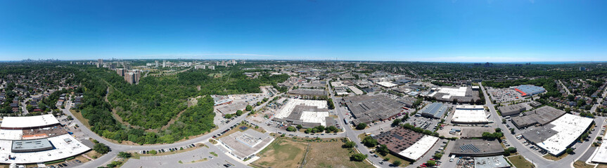Sunny summer day with plain blue sky and panoramic city landscape in Toronto, Ontario, Canada from urban industrial area to the residencies. Factories, houses, stores, parks, roads with green trees.