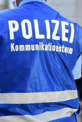 Polizeibeamter mit blauer Weste und Aufschrift: 