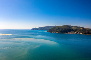 Landscape view of Tagus River mouth. Desert beach in Troia, Setubal, Portugal. Arrabida mountain in the background