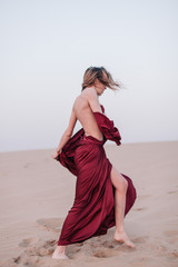 Girl with red cloth in the sunset rays in the desert