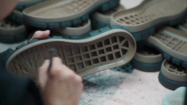 worker hand glue sole on shoes at footwear production