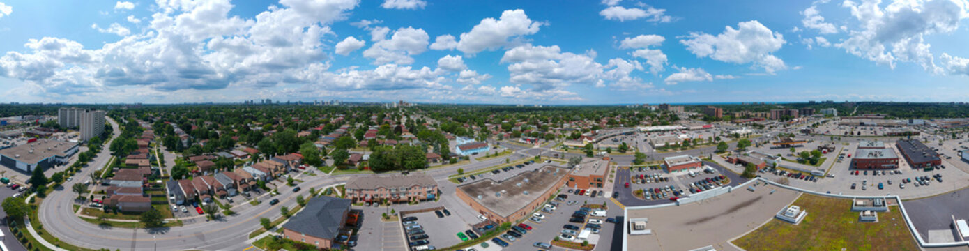 Colorful sunny day with cloudy sky. Panoramic summer landscape image of city of Toronto, Ontario, Canada. Urban wallpaper background of houses, stores, parking, and roads with green trees.