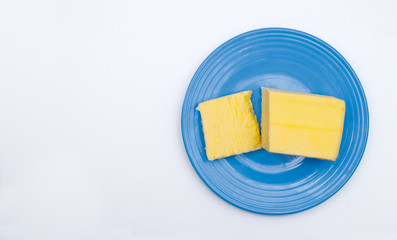 Sliced block of butter on blue plate. Top down view.