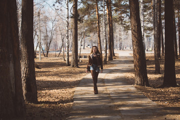 Fototapeta premium Beautiful girl with long hair walks and poses in a city park in early spring or autumn