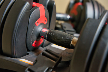 Fototapeta na wymiar Adjustable dumbbells sitting on stand. Isolated set of weights with safety straps visible.