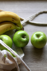 Canvas tote bag with apples and bananas. Selective focus.