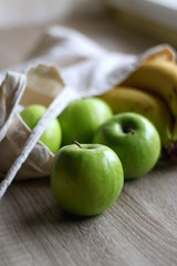 Canvas tote bag with apples and bananas. Selective focus.