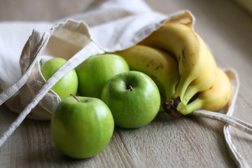 Naklejka na ściany i meble Canvas tote bag with apples and bananas. Selective focus.