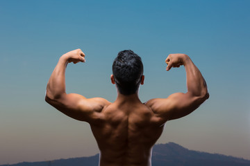 young Mexican bodybuilder back muscles posing outdoors 