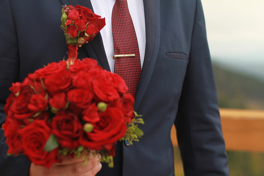 Wedding bouquet of flowers in the hands of the groom in a suit.