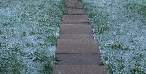 Light snow on a freshly cut lawn in mid Spring looking down a set of slippery patio stone steps